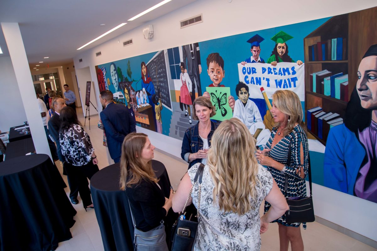 Attendees standing in front of wall mural by Artist Cbabi Bayoc