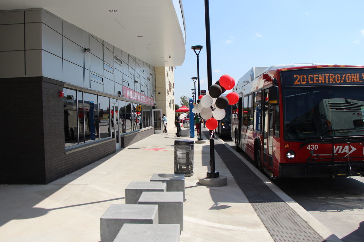 Sidewalk view of balloons on posts next to Brooks City Base Center and VIA Bus